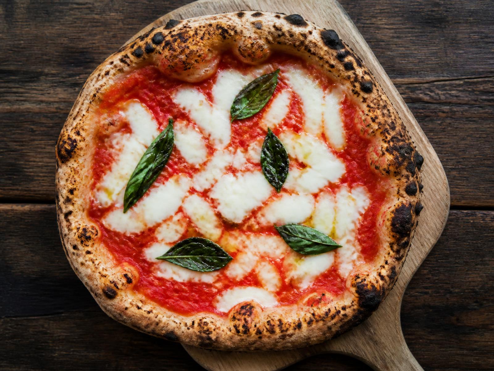 Pizza napoletana margherita con pomodoro San Marzano, mozzarella e basilico su pala di legno