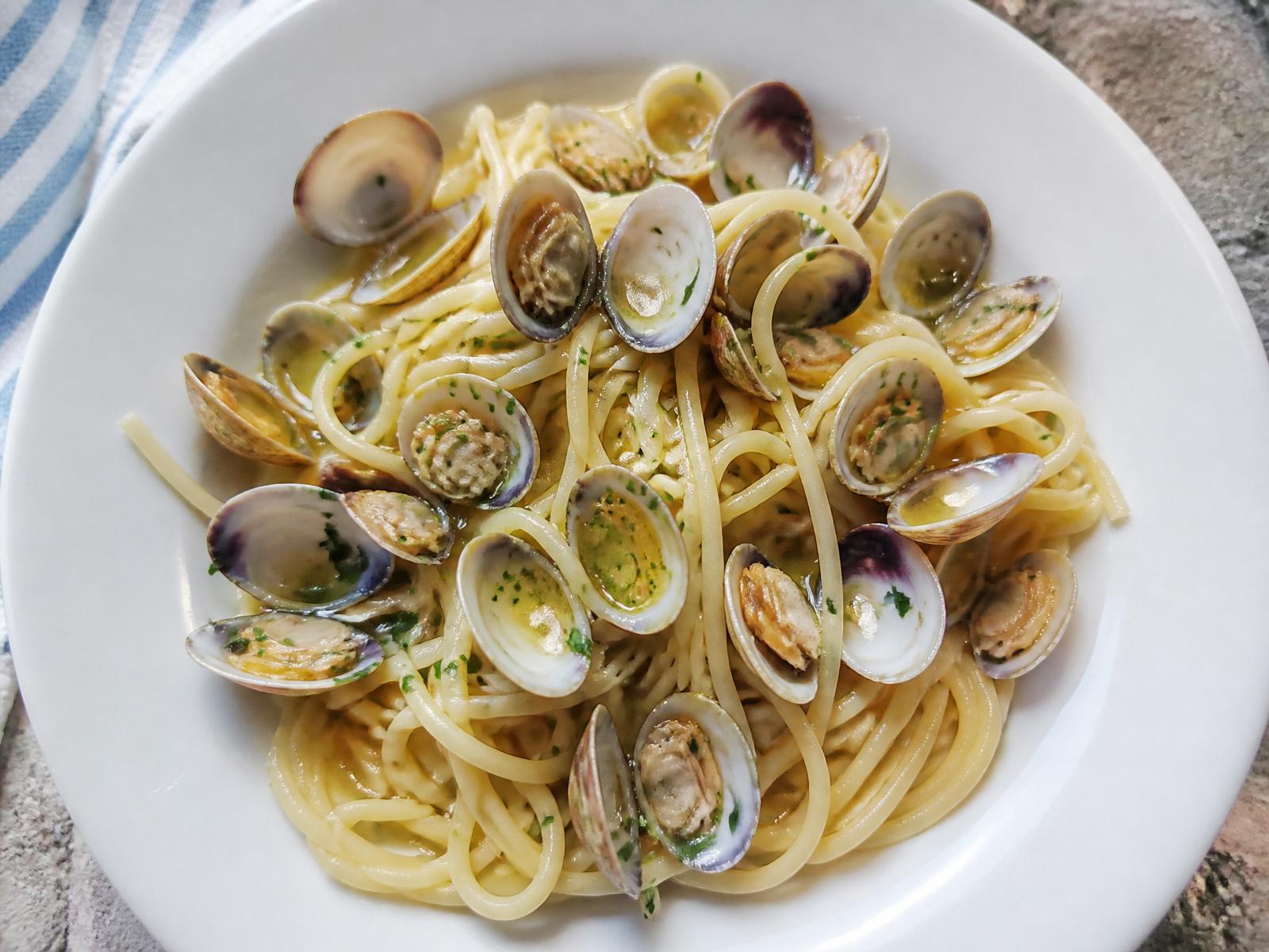 Spaghetti alle vongole in bianco con vongole veraci nelle valve, prezzemolo e olio extravergine