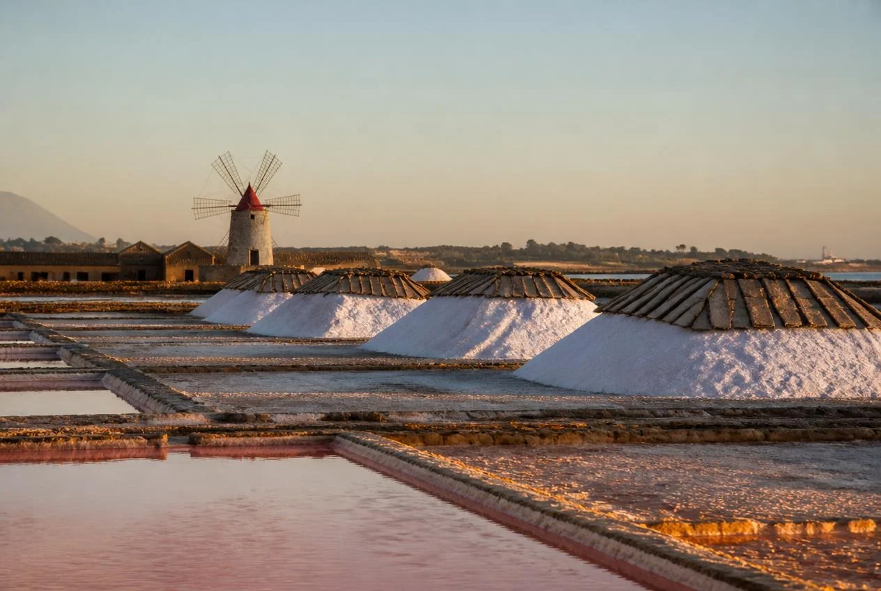 Vasche di evaporazione delle saline trapanesi con cristalli di sale e mulino a vento sullo sfondo